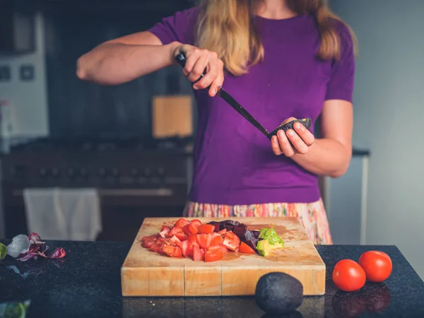 Jeune femme préparant une salade aux tomates et avocat — Photo