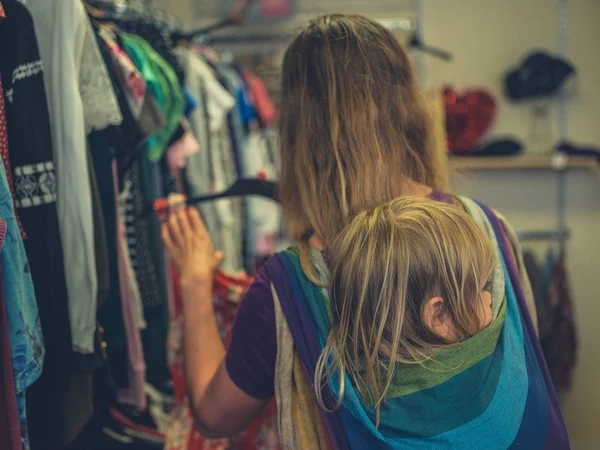 Een Jonge Duizendjarige Moeder Kleren Winkelen Met Haar Peuter Vastgebonden — Stockfoto