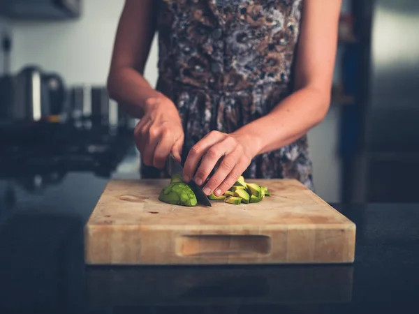 Ung kvinna hugga avokado — Stockfoto