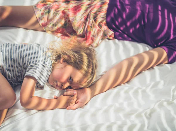 Mały Maluch Leżał Łóżku Słoneczny Dzień Trzymając Rękę Matki — Zdjęcie stockowe