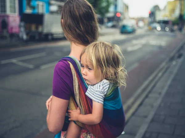 밀레니엄 어머니가 슬링에 그녀의 그녀의 유아와 거리에서 걷고있다 — 스톡 사진