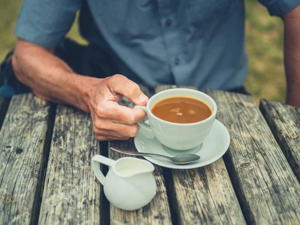 Starší Muž Pije Kávu Mlékem Venku Piknikového Stolu — Stock fotografie