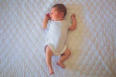 Yeni doğmuş bir bebek evde bir yatakta yatıyor.