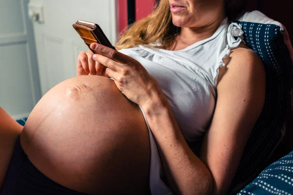 Uma Mulher Grávida Está Usando Seu Smartphone Cama — Fotografia de Stock