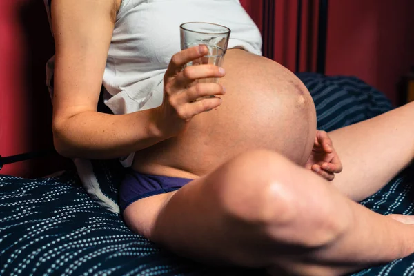 Genç Hamile Bir Kadın Bir Bardak Suyla Yatakta Oturuyor — Stok fotoğraf
