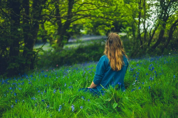 春天的时候 一个年轻的女人正在一片蓝铃花的草地上歇息 — 图库照片