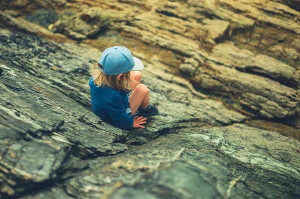 小さな未就学児が自然の中で岩の上に登っています — ストック写真