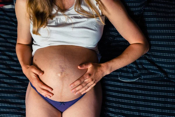 Uma Jovem Mulher Grávida Está Mentindo Uma Cama Está Sentindo — Fotografia de Stock