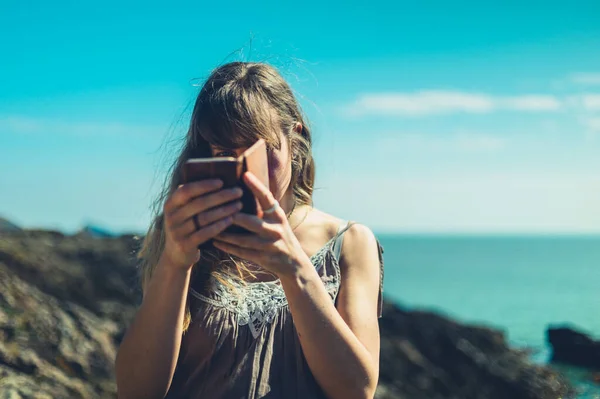 Genç Bir Kadın Güneşli Bir Günde Deniz Kenarında Akıllı Telefonunu — Stok fotoğraf