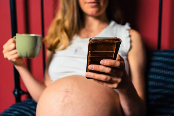 Молодая Беременная Женщина Пьет Кружки Использует Свой Смартфон Постели — стоковое фото