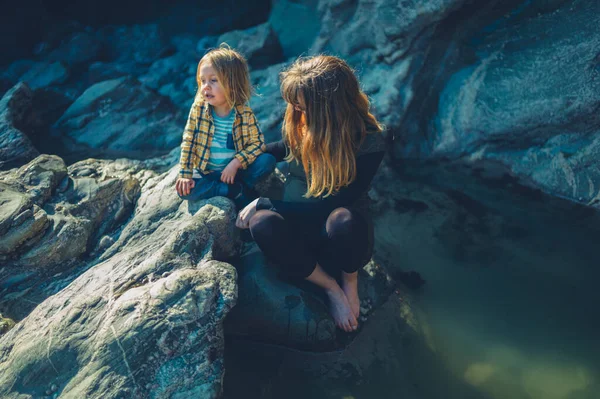 若い母親と彼女の未就学児は春に岩のプールに座っています — ストック写真