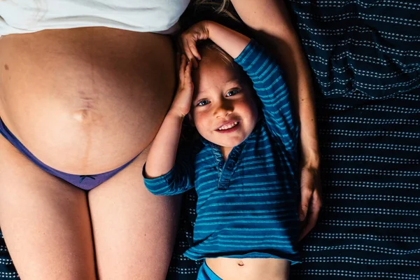 Menino Está Deitado Lado Sua Mãe Grávida Cama — Fotografia de Stock