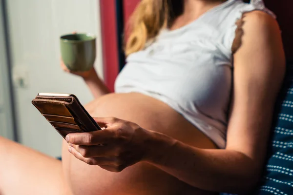 Молодая Беременная Женщина Пьет Кружки Использует Свой Смартфон Постели — стоковое фото