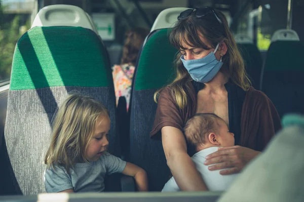 2人の子供を持つ母親が電車の中でフェイスマスクをしています — ストック写真