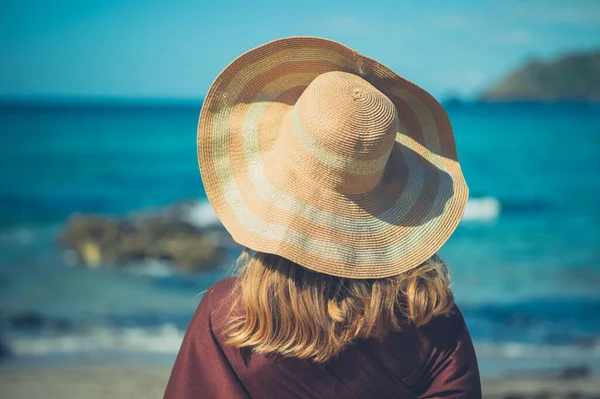 一个年轻的女人在海边戴着一顶草帽 — 图库照片