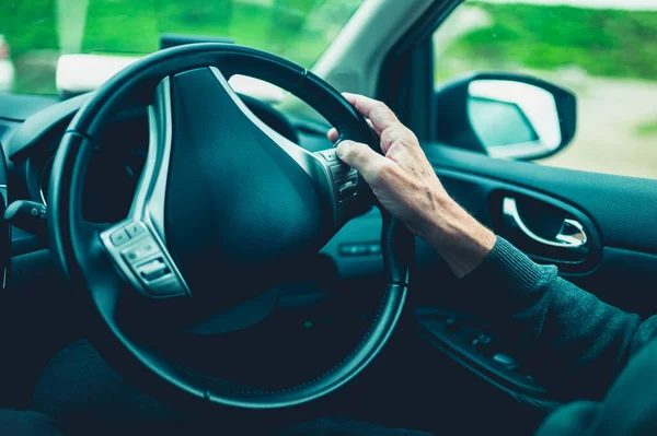 Arabadaki stering çarkında kıdemli bir adamın eli.