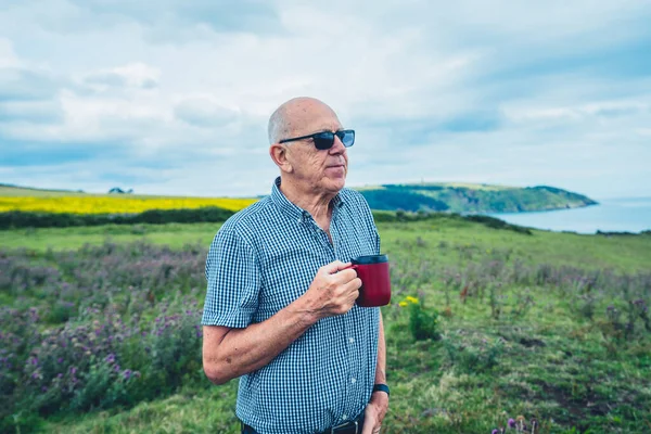 노인이 바닷가 초원에서 커피를 마시고 — 스톡 사진