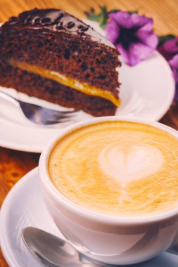 Taze kapuçino Sacher kek ahşap masa üzerine lezzetli parça ile kahve fincan