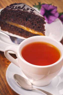 Bir fincan taze çay lezzetli parça ahşap masa üzerinde Sacher pastası ile