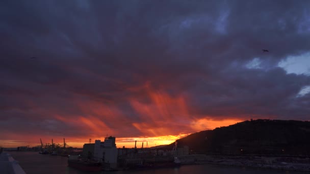 Donker blauwe, paarse en rode stormachtige hemel achtergrond bij zonsondergang met verbluffende levendige Cloud vorming met de kustlijn van Barcelona in 4k — Stockvideo