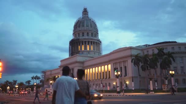 Havana, Kuba-13. května 2018-El Capitolio při západu slunce se starožitamerickými auty a lidmi v ulicích 4 k — Stock video