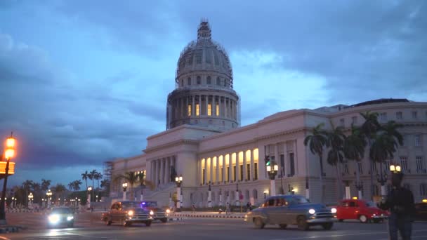 Havana, Kuba-13. května 2018-El Capitolio při západu slunce se starožitamerickými auty a lidmi v ulicích 4 k — Stock video