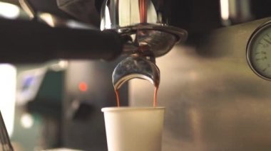 Kahve makinesi ağır çekimde sıcak espresso kahvesi dolduruyor.