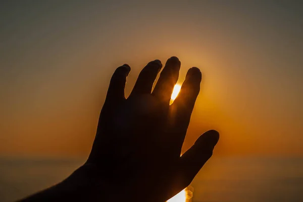 silhouette hands against the sun