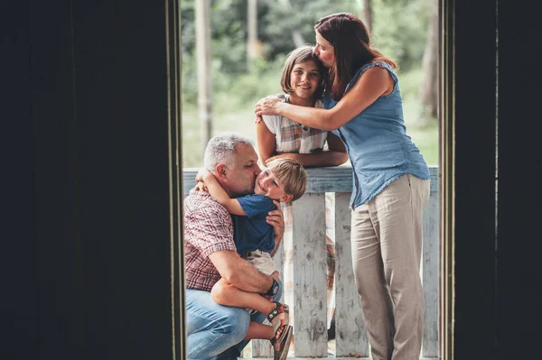 Aile evin verandasında sarılıyor.