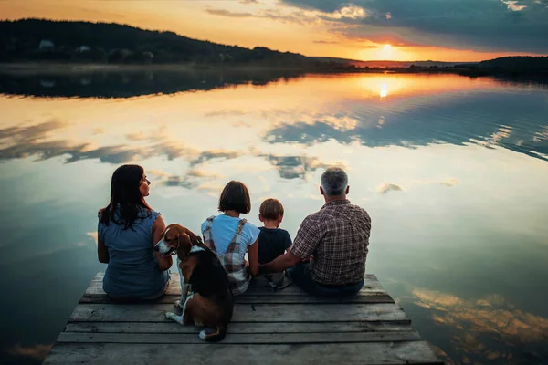 Aile gün batımında büyük bir gölün kıyısında oturur.