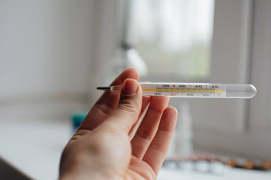 İlk yardım çantasının ve çeşitli ilaçların arka planında el termometresi var.