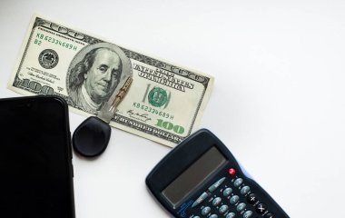 Beyaz ekranlı, hesaplayıcı anahtar telefon. Beyaz arka planda 100 dolar.