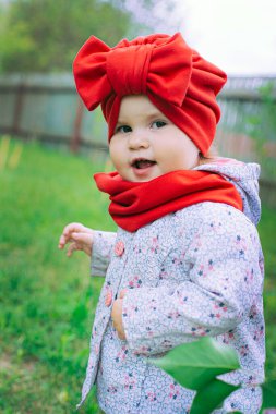 Kırmızı şapkalı küçük kız bahçede mor leylağın yanında.