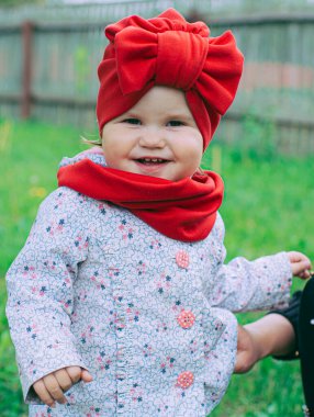 Kırmızı şapkalı küçük kız bahçede mor leylağın yanında.