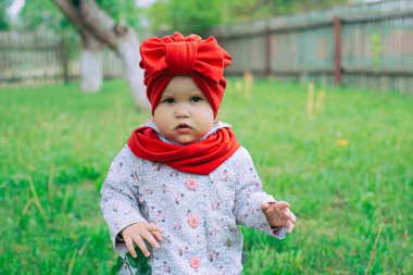 Kırmızı şapkalı küçük kız bahçede mor leylağın yanında.