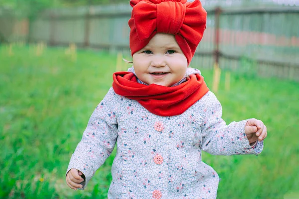 Kırmızı şapkalı küçük kız bahçede mor leylağın yanında.