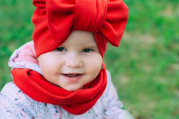 Kırmızı şapkalı küçük kız bahçede mor leylağın yanında.