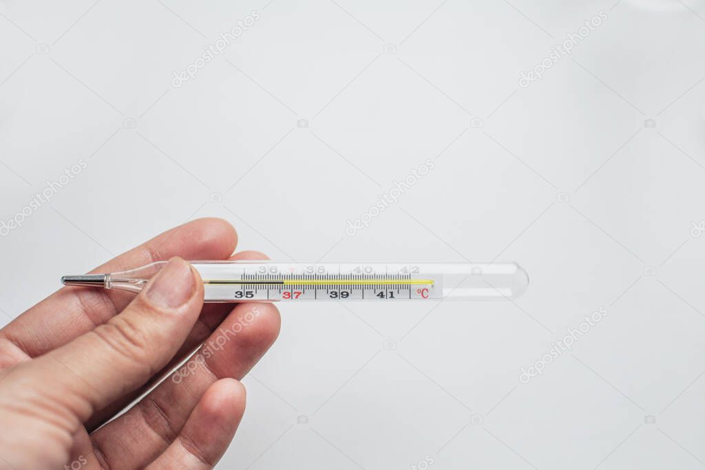 thermometer in hand on a homogeneous background close up 