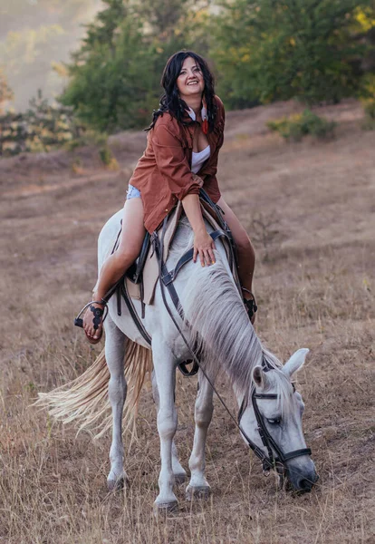 一个穿着牛仔服装 骑着马在草坪上的女孩 — 图库照片