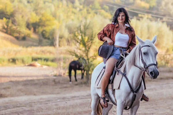 一个穿着牛仔服装 骑着马在草坪上的女孩 — 图库照片