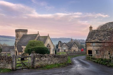 Cotswolds Gloucestershire 'daki Snowshill kilisesinde kırmızı telefon kulübesi ve köy barına doğru giden bir kulübeye giden bir şerit var.