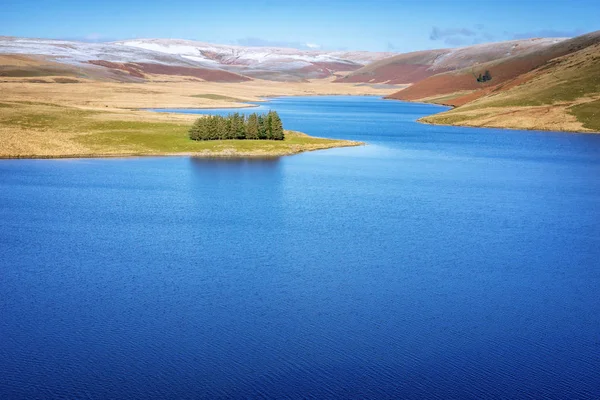 Craig Goch resevoir v Elan Valley Wales se zasněženými horami a stromy. Voda na dodávku birminghamu odrážející modrou oblohu — Stock fotografie