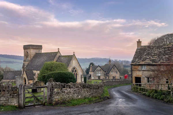 Cotswolds Gloucestershire 'daki Snowshill kilisesinde kırmızı telefon kulübesi ve köy barına doğru giden bir kulübeye giden bir şerit var.