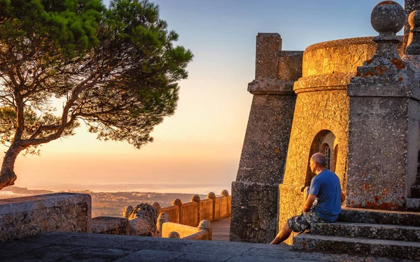 San Salvador Mallorca. Tourist admires view at cycling destination next to monument and lone tree at the top of the hill at sunrise.