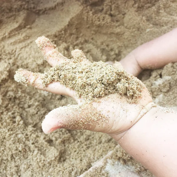 Sand in hand child age 2 years.