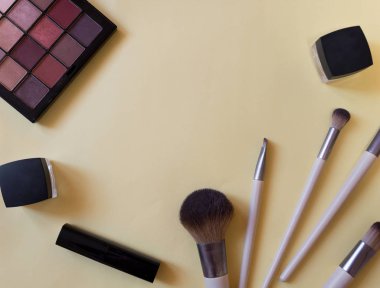 Pembe arka planda bir kozmetik tüpler ve krem kapları üst görünümü kavramı. Ruj, fırça, palet. Merkezde yazıt için yer .