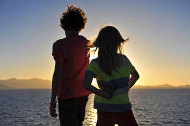 Sunset'teki denizde iki çocuk silüeti