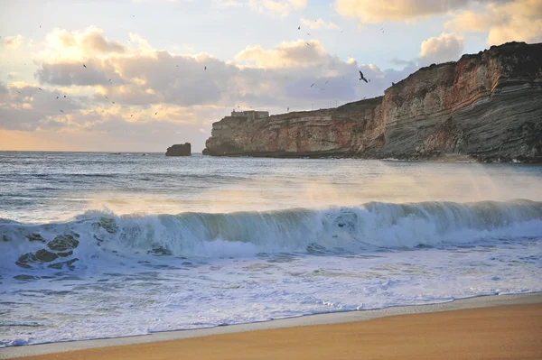 Spiaggia Nazare e faro sulle scogliere al tramonto — Foto Stock