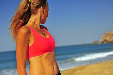 Kumsalda duran genç bir kadın.