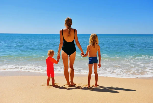 Young woman standing on beach with her kids — Stock Photo, Image